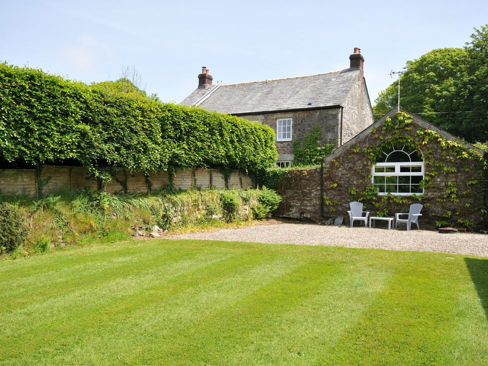 A garden with a house and seating area at Trevenning Chapel Near Port Isaac