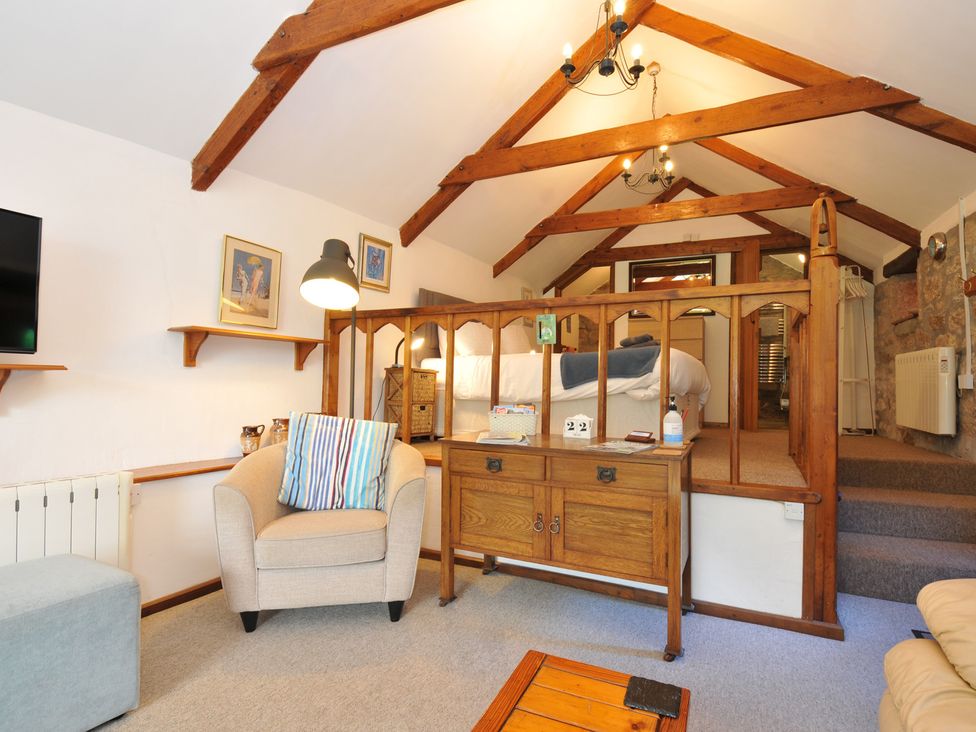 A living room with furniture and a bed area at Trevenning Chapel near Port Isaac
