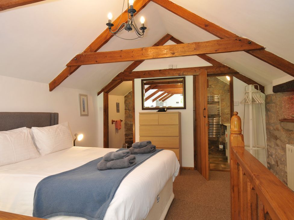 A bedroom with a bed and wooden furniture at Trevenning Chapel Near Port Isaac