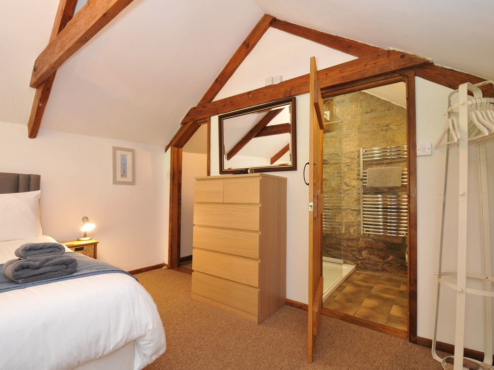 A bedroom with a dresser and a bathroom door at Trevenning Chapel near Port Isaac