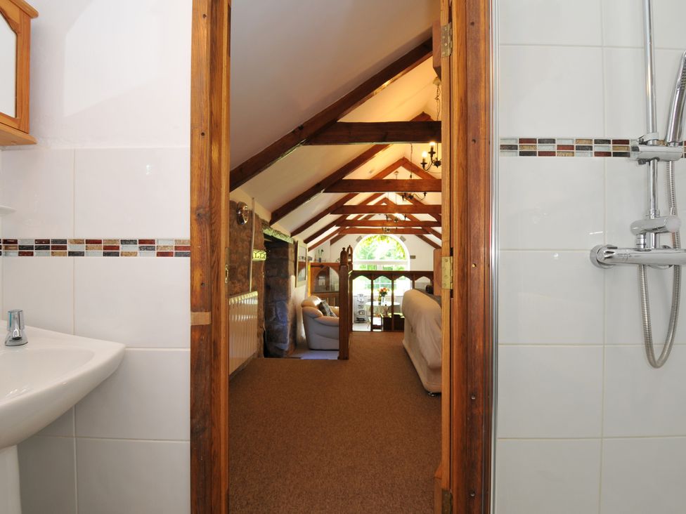 A bathroom with a wash basin and shower leading to a living room at Trevenning Chapel Near Port Isaac