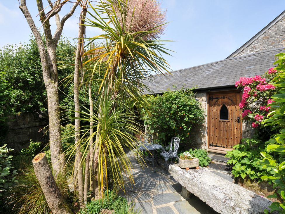 A garden with plants and a stone bench at Trevenning Chapel near Port Isaac