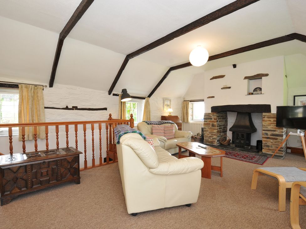 A living room with a fireplace and sofa at Trevenning Barn near Port Isaac