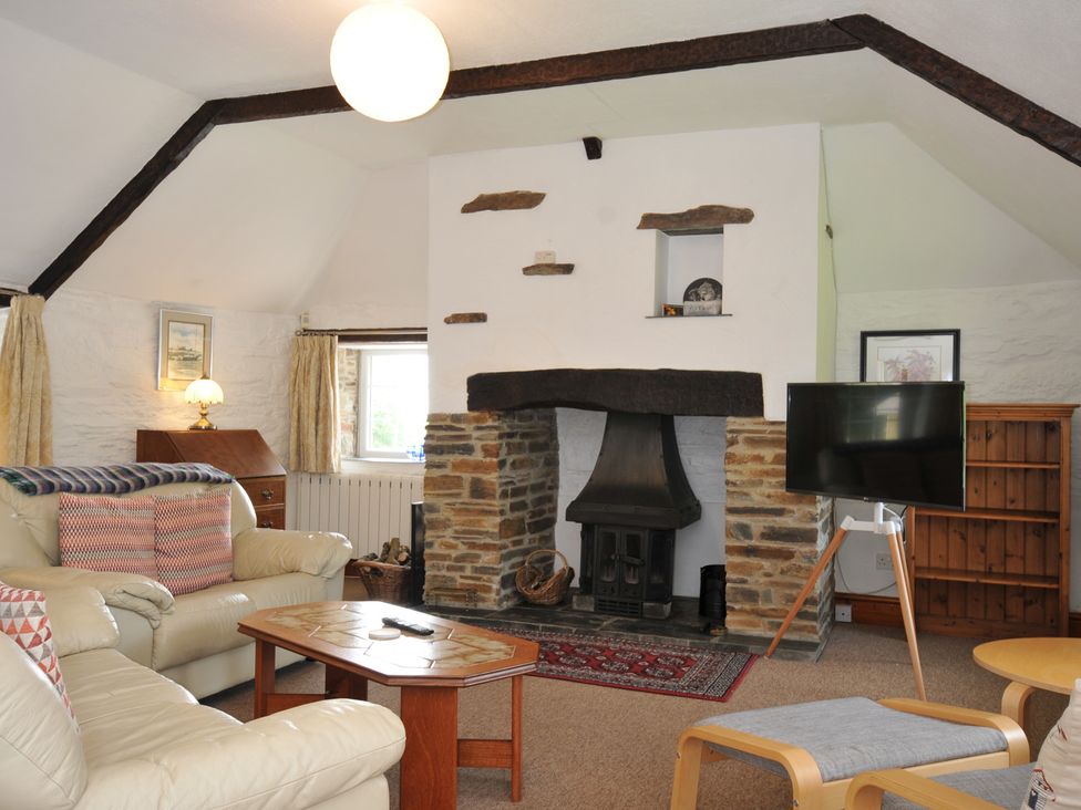 A living room with a fireplace and sofa at Trevenning Barn near Port Isaac