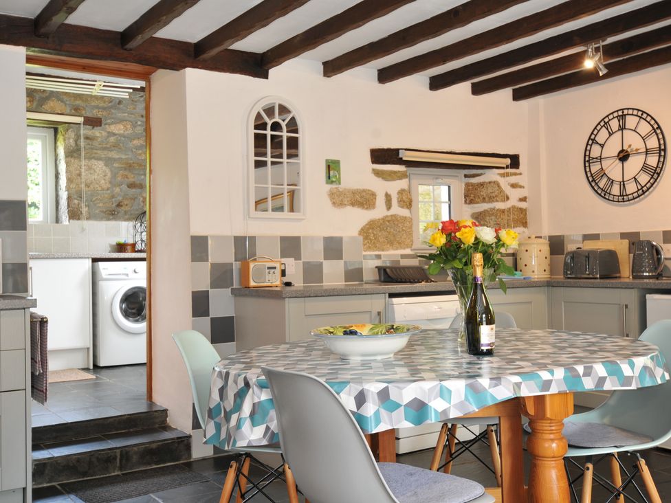 A kitchen with a table and flowers at Trevenning Barn Near Port Isaac