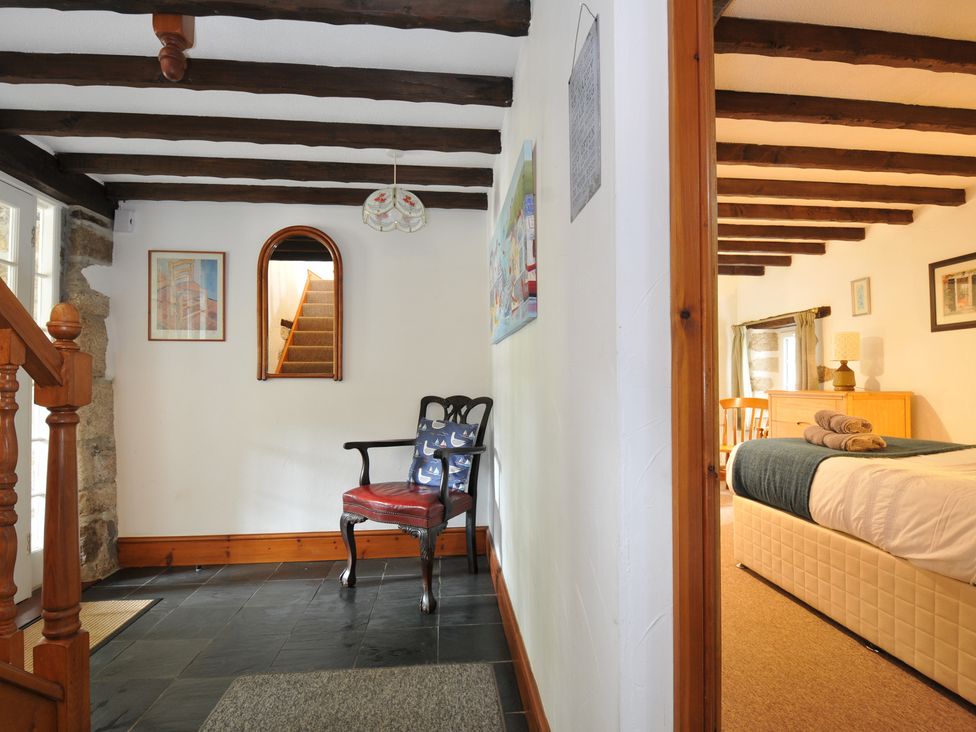 A hallway with a staircase and a chair at Trevenning Barn Near Port Isaac