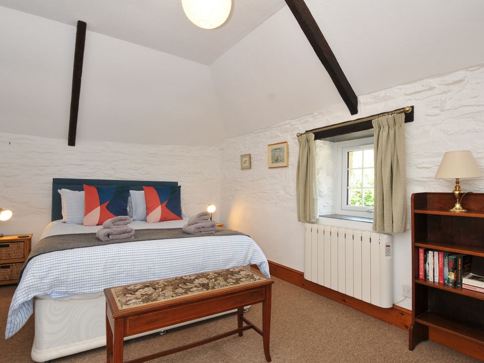 A bedroom with a bed and bookshelf at Trevenning Barn Near Port Isaac
