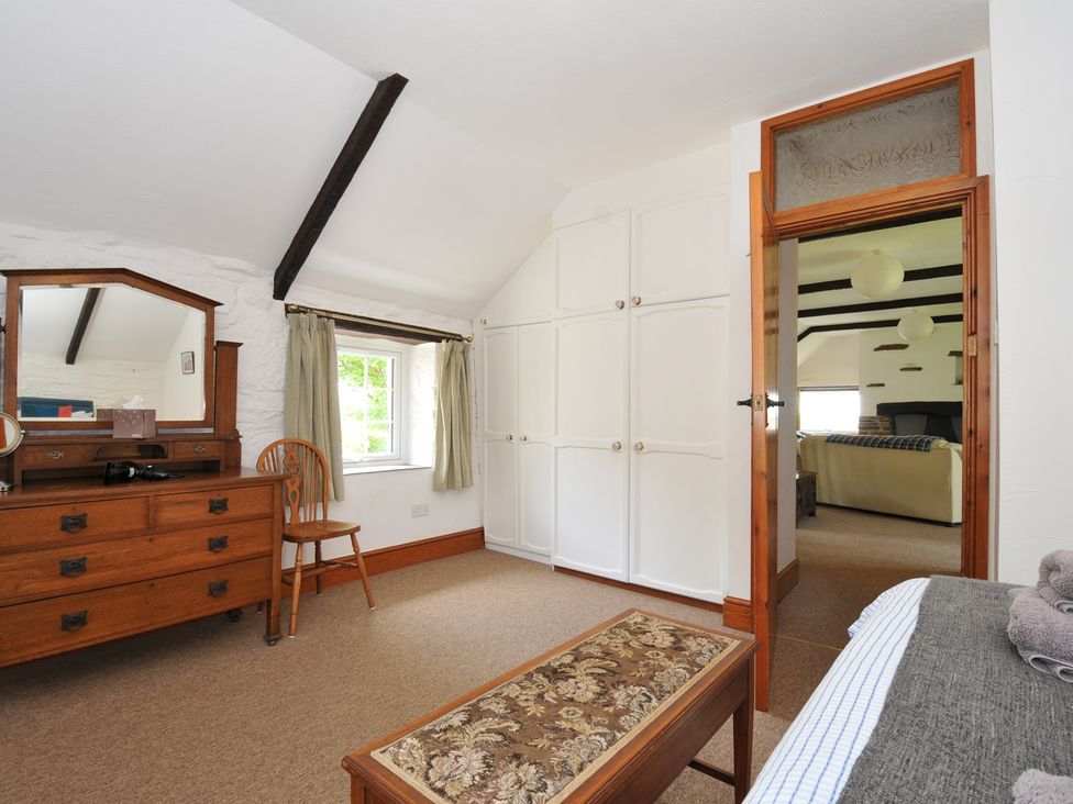 A bedroom with a dresser, mirror, and wardrobe at Trevenning Barn Near Port Isaac