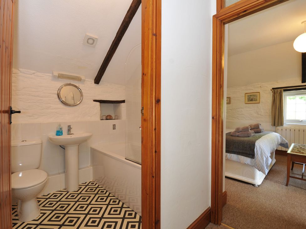 A bathroom with a sink and toilet leading to a bedroom at Trevenning Barn near Port Isaac