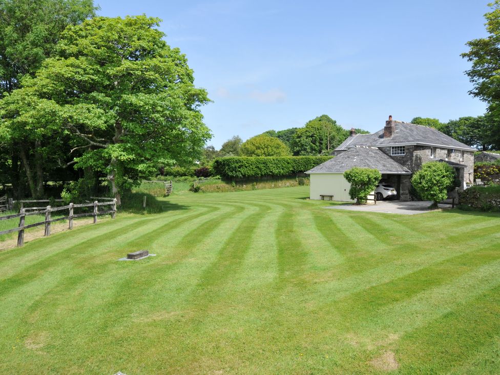 A garden with a house and trees at Trevenning Barn near Port Isaac