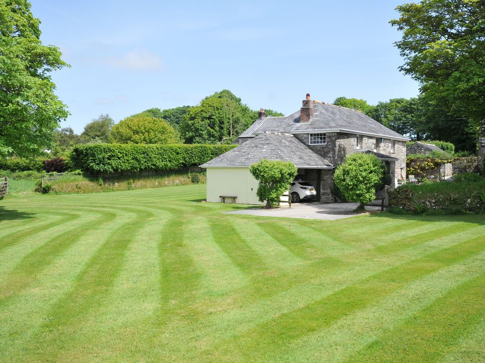 A house with a lawn and trees at Trevenning Barn Near Port Isaac
