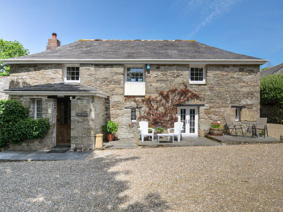 An outdoor area with stone wall, chairs and table at Trevenning Barn near Port Isaac