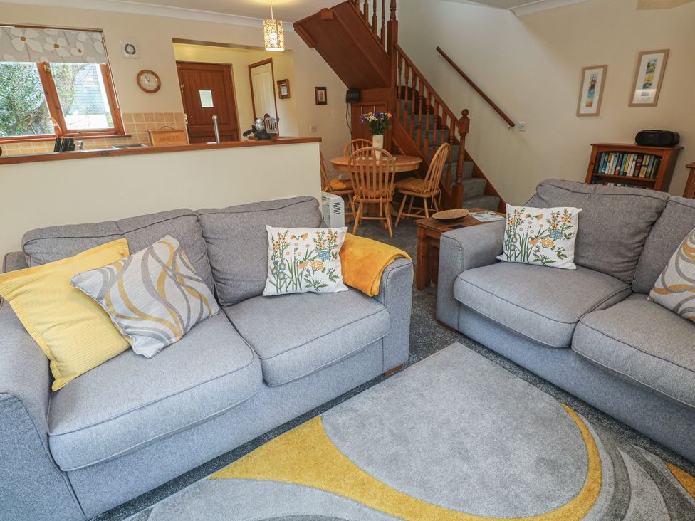 A living room with sofas and a dining area at Two Hoots in Falmouth