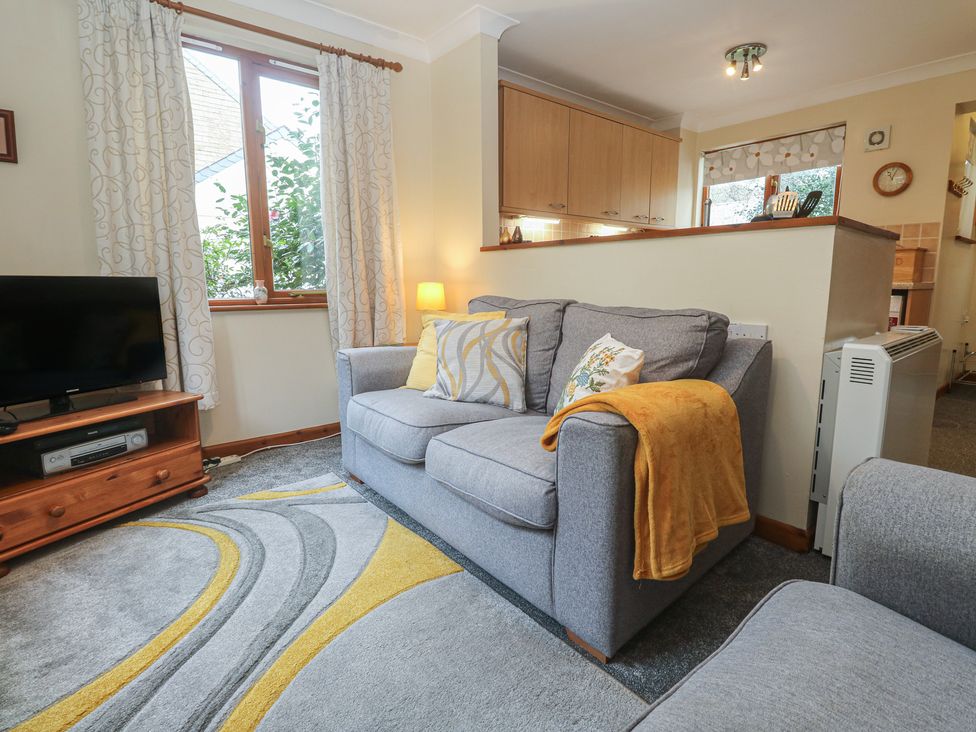 A living room with a sofa and television at Two Hoots in Falmouth