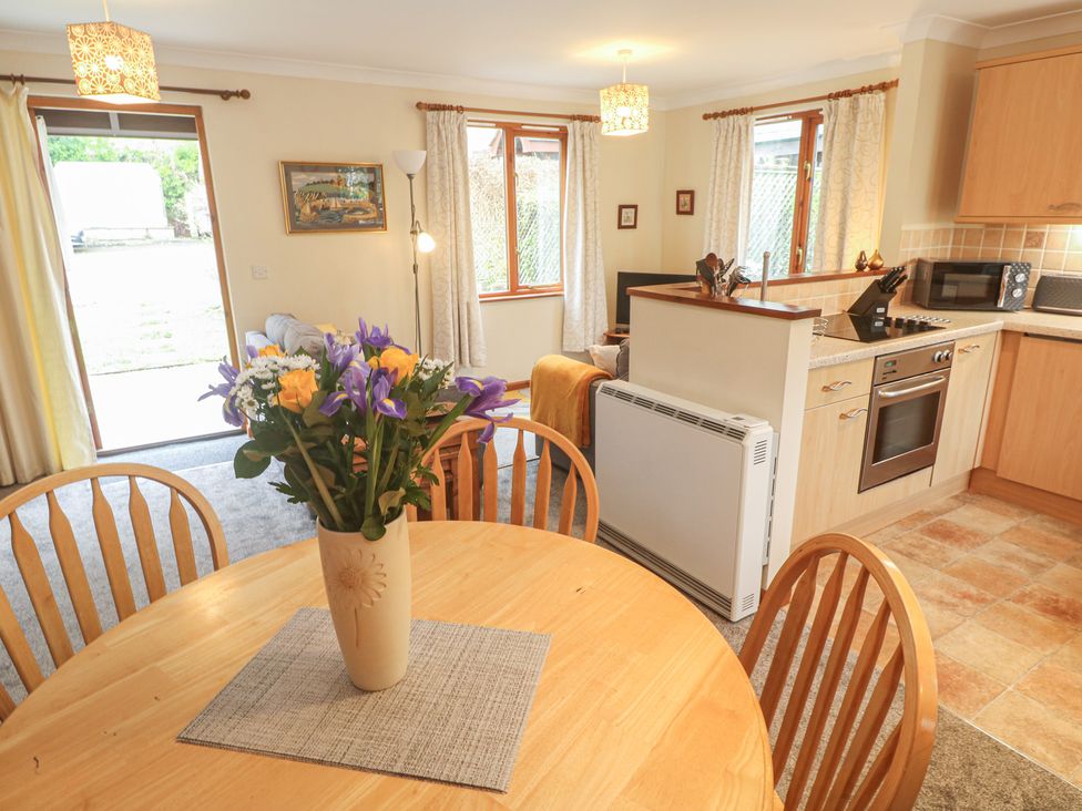 A dining room with a table and kitchen area at Two Hoots in Falmouth