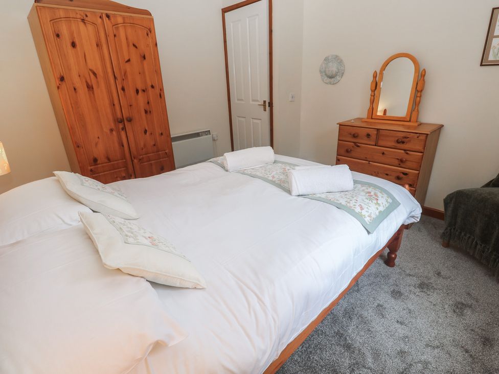A bedroom with a bed and wardrobe at Two Hoots in Falmouth