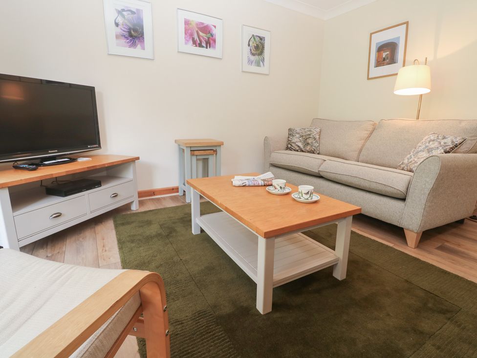 A living room with a television and sofa at Sild Cottage in Falmouth