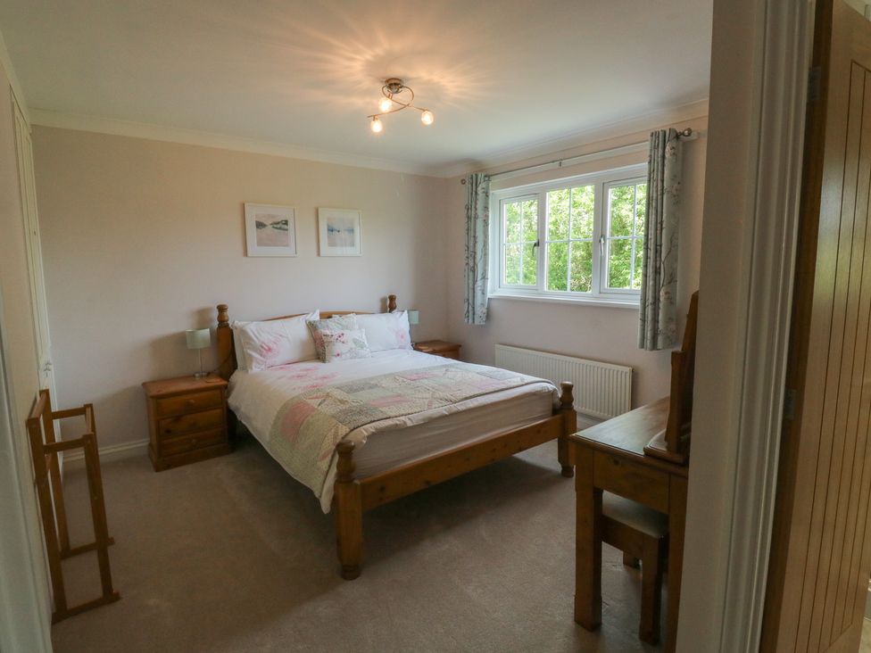 A bedroom with a bed and windows at Glebe House in Bigbury