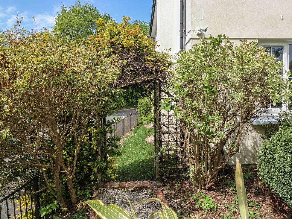 A garden pathway with shrubs and a trellis at Glebe House in Bigbury
