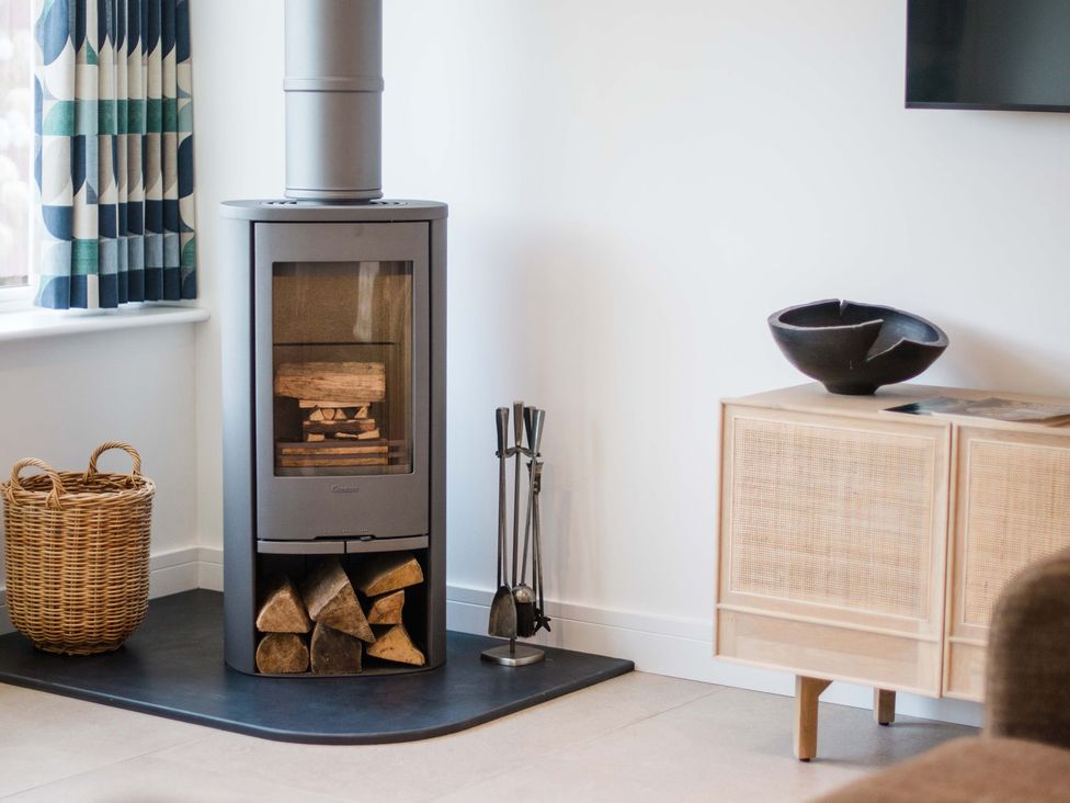 A living room with a wood stove and a sideboard at Lanesend St Agnes
