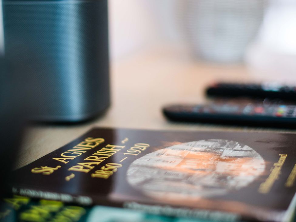 A speaker, book, and remote controls on a table at Lanesend in St Agnes