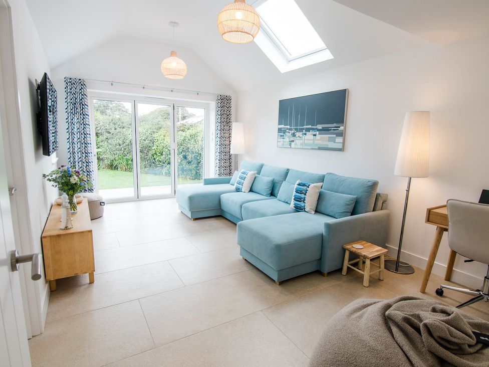 A living room with a blue sofa and glass door at Lanesend in St Agnes