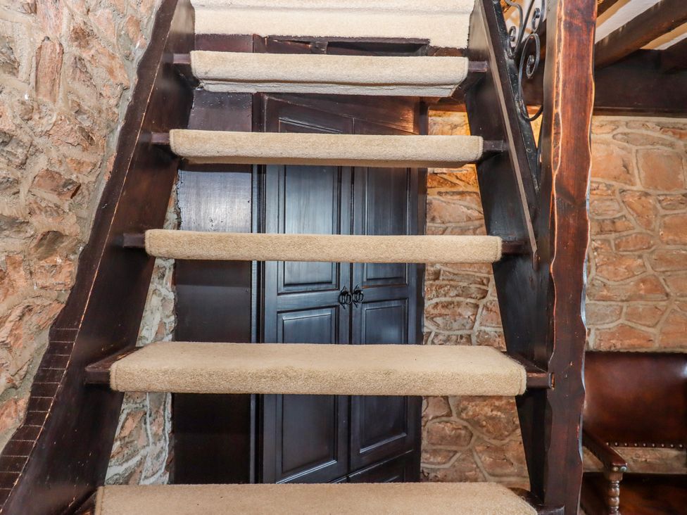 A staircase with carpeted steps and a wooden railing at Blue Horizon in Brixham