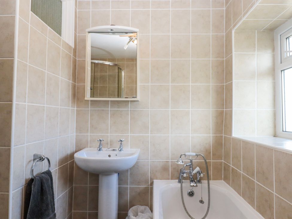A bathroom with sink, mirror, and bathtub at Blue Horizon in Brixham