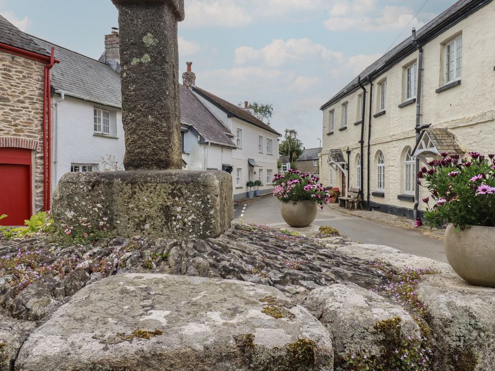 A street with a stone cross and flower pots at Trelan in Mevagissey