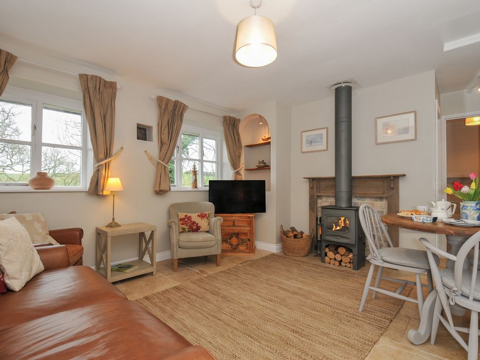 A living room with a fireplace and dining table at Stocks Barn in Looe