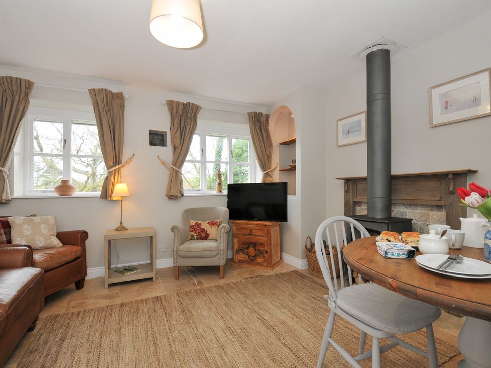 A living room with a sofa, armchair, and dining table at Stocks Barn Looe