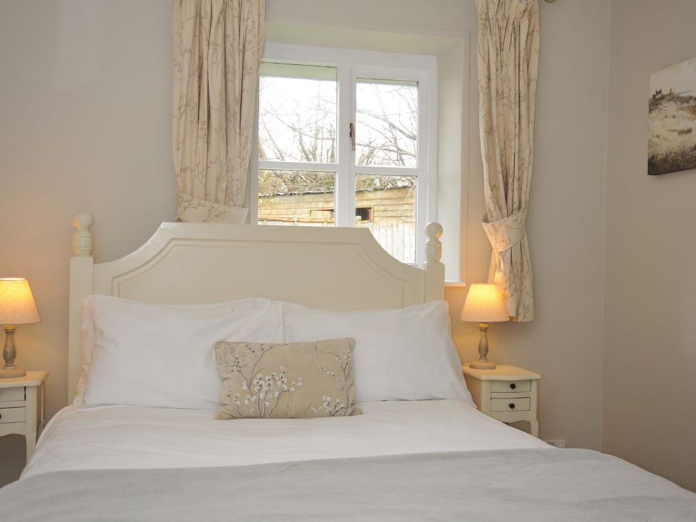 A bedroom with a bed and lamps at Stocks Barn in Looe