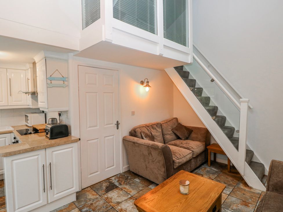 A living room with a sofa and staircase at Trelessy Lodge near Llanteg