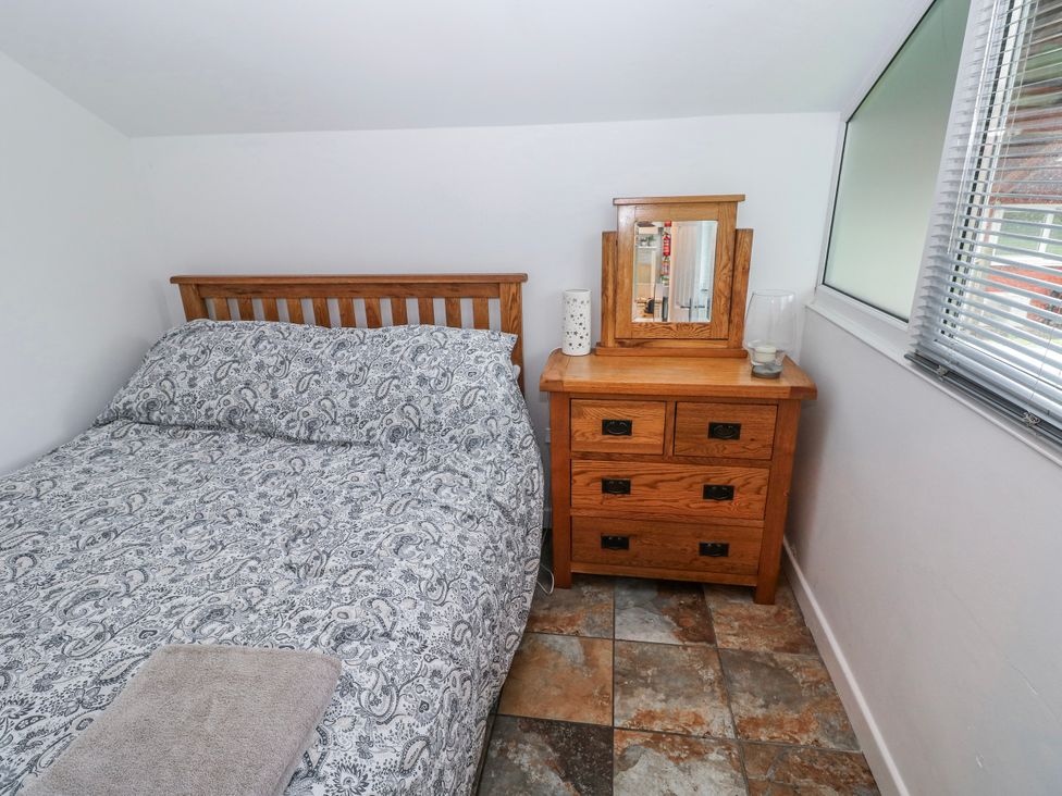 A bedroom with a bed and a bedside table at Trelessy Lodge in Llanteg near Amroth