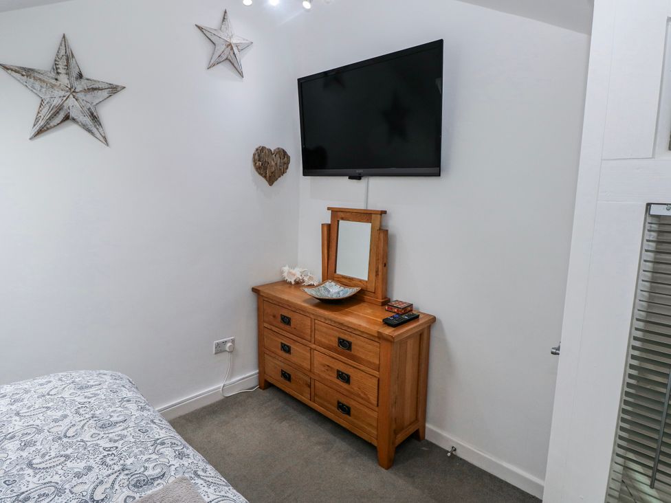 A bedroom with a dresser and television at Trelessy Lodge in Llanteg near Amroth