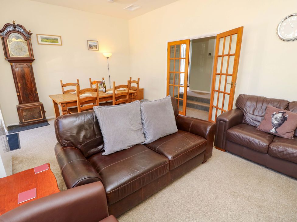 A living room with a sofa and dining area at The Stable Cottage in Wroxall