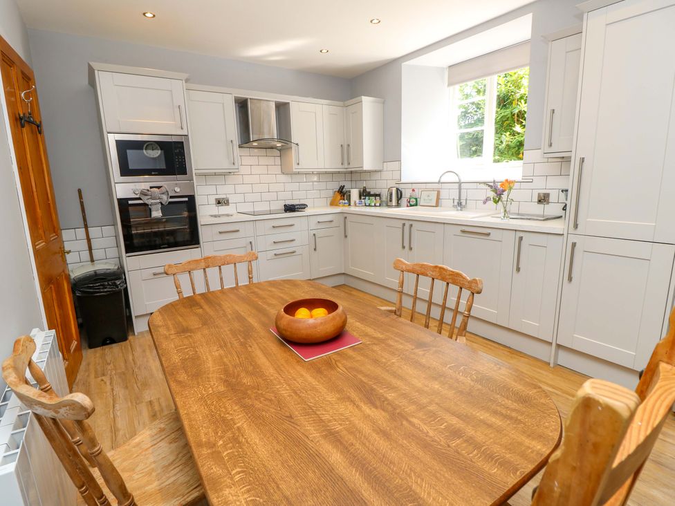 A kitchen with a dining table and kitchen cabinets at The Stable Cottage in Wroxall