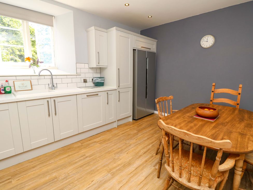 A kitchen with cabinets and a dining table at The Stable Cottage Wroxall
