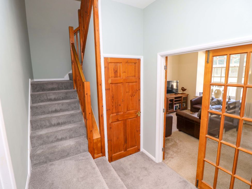 A hallway with stairs and doors leading to a living room at The Stable Cottage in Wroxall