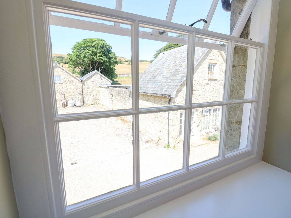 A view from a window showing stone buildings and a tree at The Stable Cottage in Wroxall