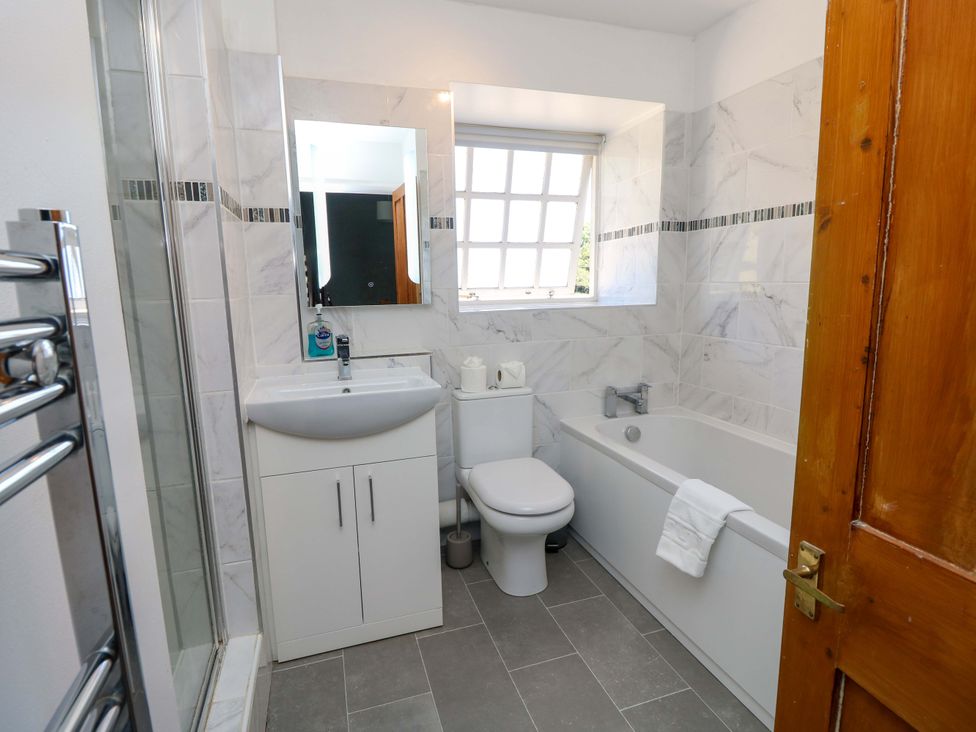 A bathroom with a bathtub, shower, sink, and toilet at The Stable Cottage in Wroxall