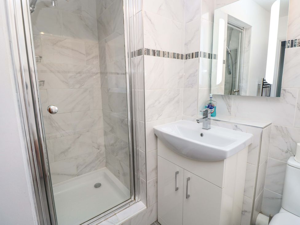 A bathroom with a shower, sink, mirror, and toilet at The Stable Cottage in Wroxall