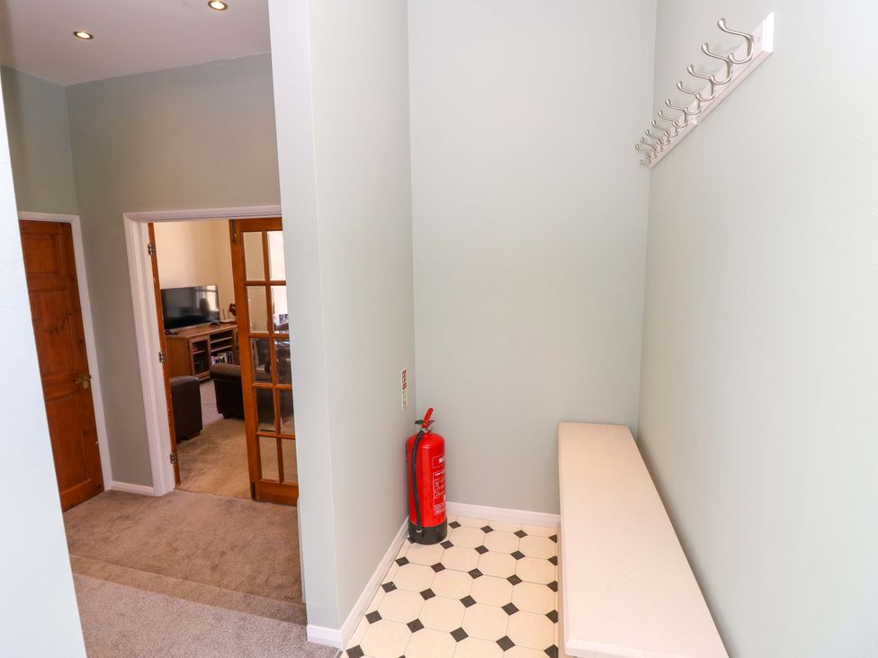 A hallway with a bench and coat hooks at The Stable Cottage in Wroxall