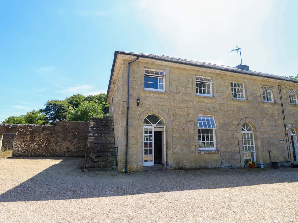 An outdoor view of a stone building with a driveway at The Stable Cottage in Wroxall