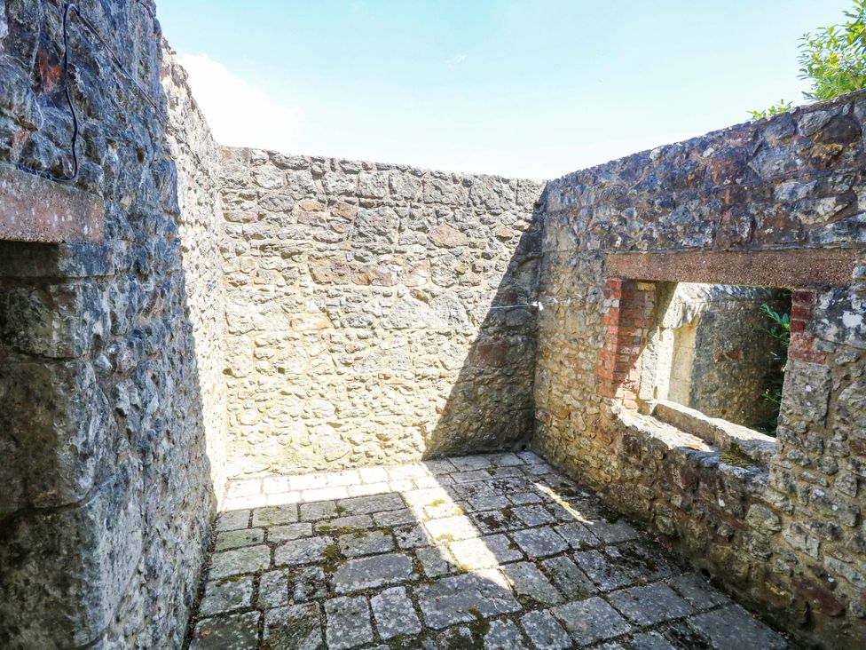 An open space with stone walls and floor tiles at The Stable Cottage in Wroxall