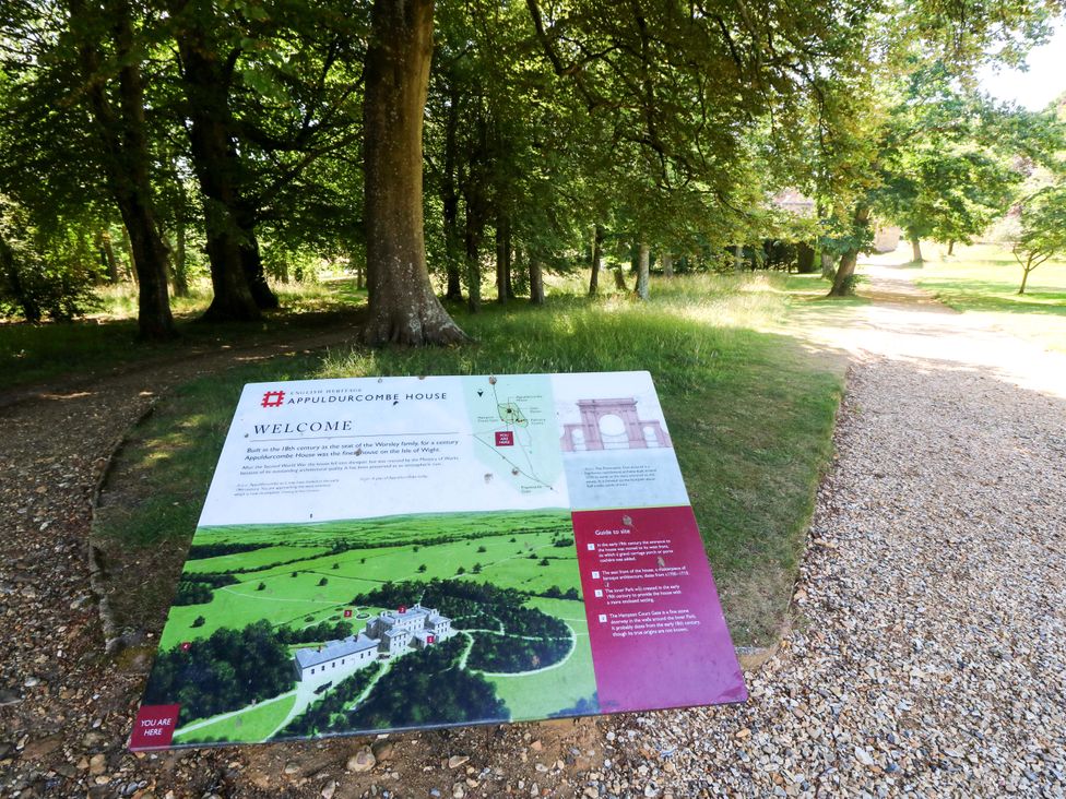 A sign with information about Appuldurcombe House near a gravel path in Wroxall