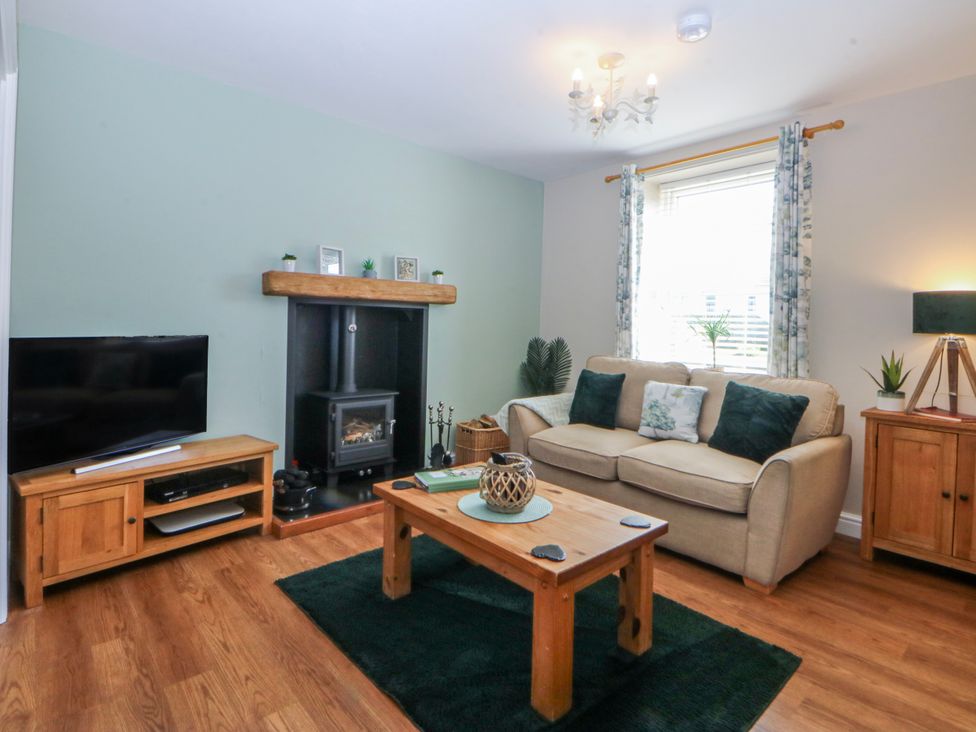 A living room with a television and fireplace at Bythynnod Newydd in Trefor near Nefyn