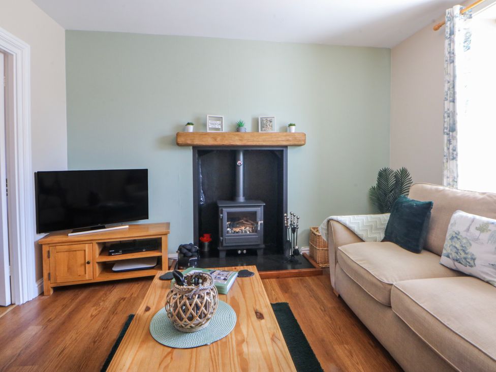 A living room with a television and sofa at Bythynnod Newydd in Trefor near Nefyn