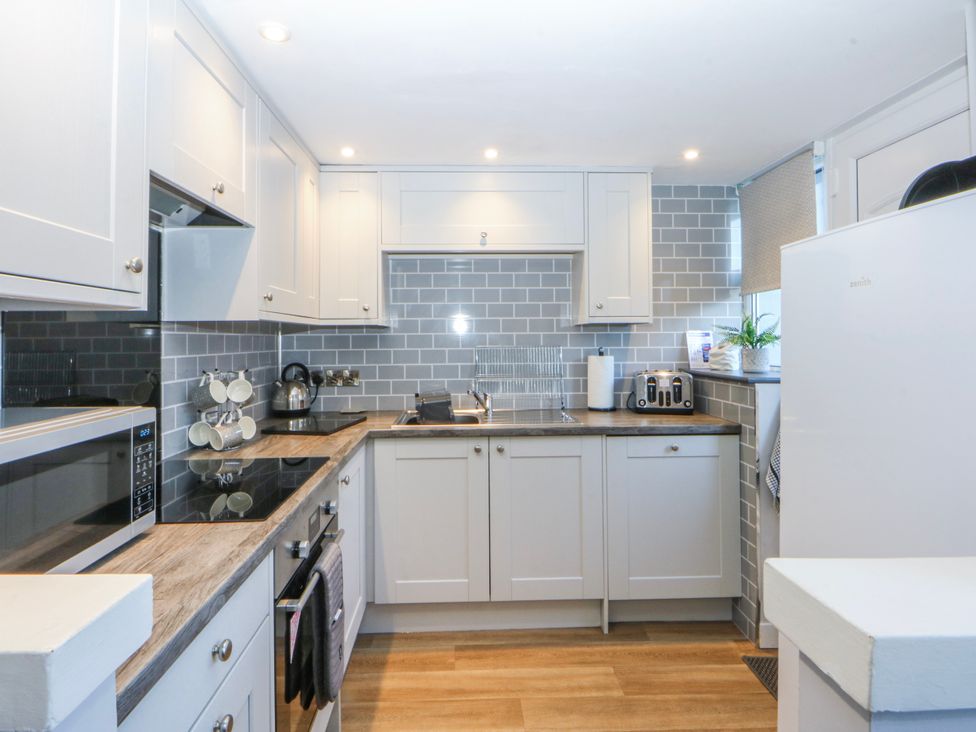 A kitchen with cabinets, appliance and sink at Bythynnod Newydd Trefor near Nefyn
