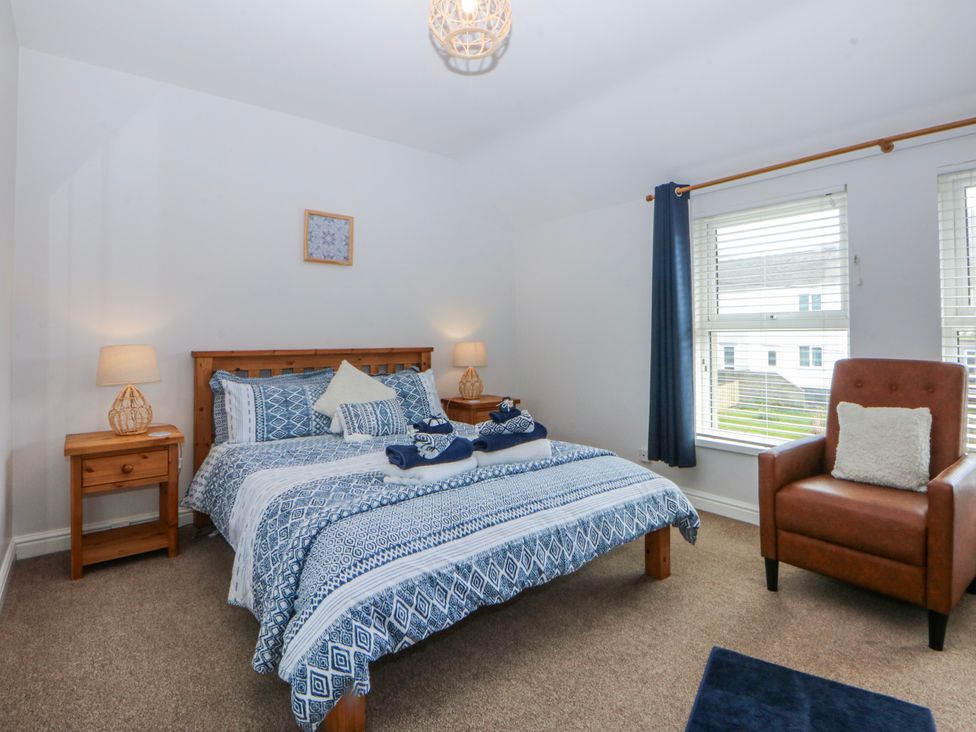 A bedroom with a bed and chair at Bythynnod Newydd Trefor near Nefyn